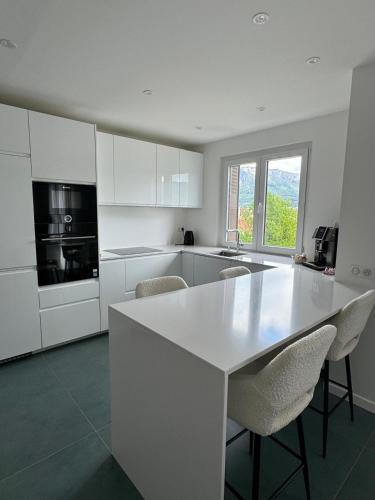 une cuisine blanche avec une table et des chaises blanches dans l'établissement Spatieux T3 60m2 Annecy - Parking Privé - WIFI - Netflix, à Annecy