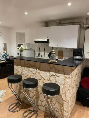 une cuisine avec un bar avec trois tabourets dans l'établissement Agréable Appartementbuttes-Chaumont, à Paris