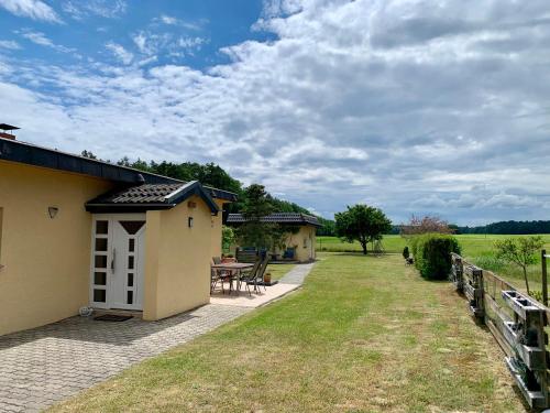 a house with a patio and a table in the yard at Idyllisches Ferienhaus in ruhiger Lage in Wölsickendorf-Wollenberg