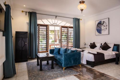 een slaapkamer met een bed en een blauwe bank bij Coconut Residence & Spa in Kololi