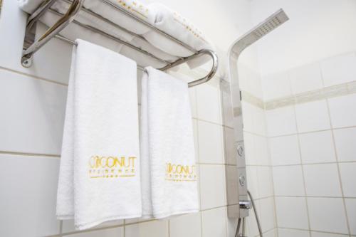 een badkamer met witte handdoeken op een douchegordijn bij Coconut Residence & Spa in Kololi