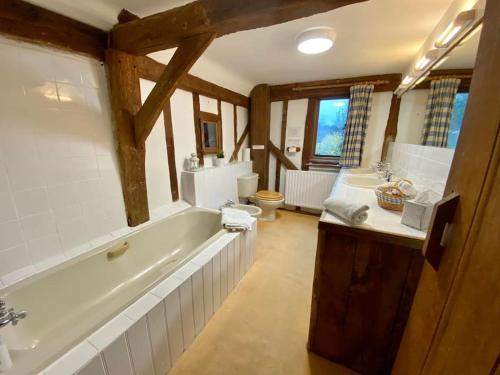 a bathroom with a bath tub and two sinks and a tub at DADIO's Barn - Indoor Swimming Pool 400 Years Old & Hot tub in Kent