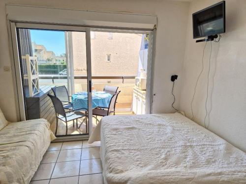 une chambre avec un lit et un balcon avec une table dans l'établissement Studio Cabine avec Piscine, Terrasse et Parking, Proche Commodités - FR-1-387-206, à Marseillan