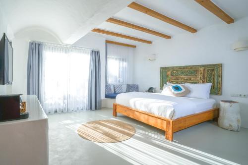 Kassandra Boutique Hotel في أولدينيس: غرفة نوم بيضاء مع سرير ونافذة كبيرة