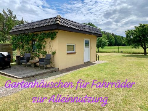 a small shed with a table and chairs in a yard at Idyllisches Ferienhaus in ruhiger Lage in Wölsickendorf-Wollenberg