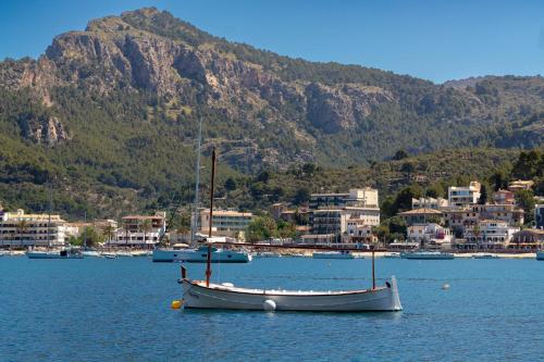 a boat sitting in the water near a city at Hotel Boutique Minister 4Sup in Port de Soller