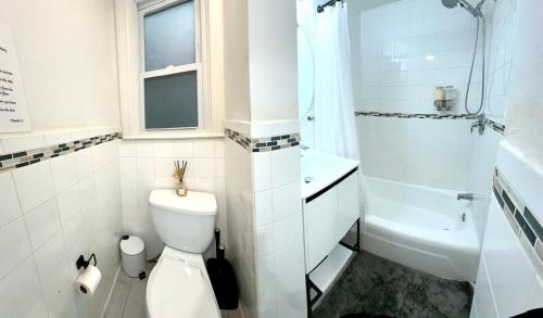 a white bathroom with a toilet and a sink at 2-A Diamond in Yonkers in Yonkers