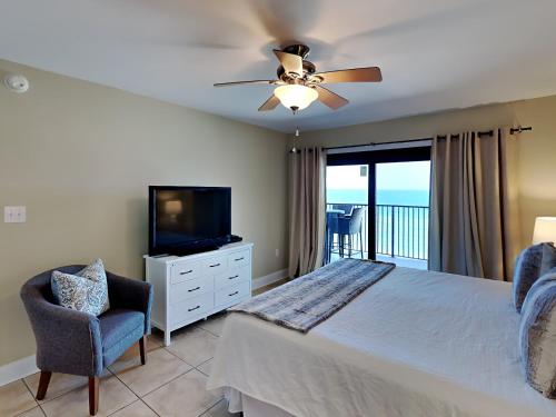a bedroom with a bed and a television and a chair at Ocean Breeze East #802 in Perdido Key