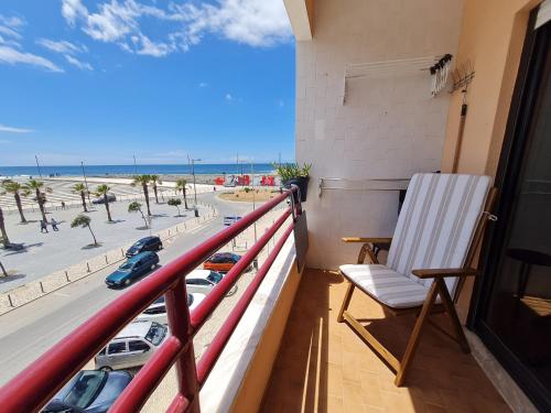 a balcony with a chair and a view of the beach at Beach Addiction in Costa da Caparica