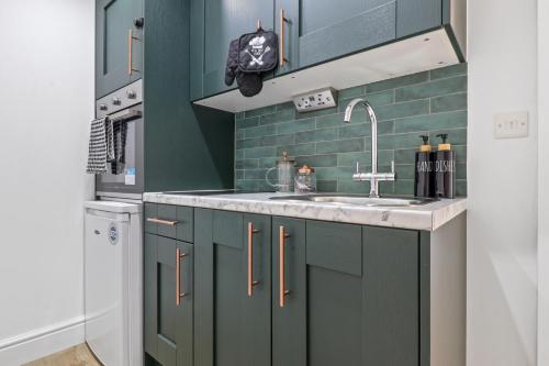 uma cozinha com armários verdes e um lavatório em Finsbury Park Studios em Londres