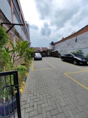 two cars parked in a parking lot next to a building at Pondok Syariah Hadikusuma in Rahayu
