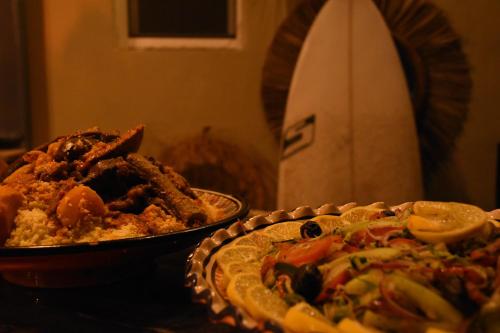 a table with two plates of food on it at Playa Del Sol Surf House in Tamraght Ouzdar