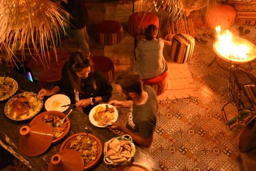 a group of people sitting around a table with food at Playa Del Sol Surf House in Tamraght Ouzdar