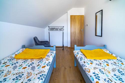 2 camas en una habitación con silla en Całoroczny Domek Bosmańska, en Lubiatowo