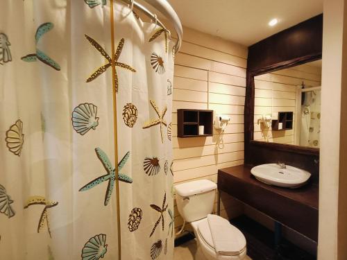 a bathroom with a shower curtain and a toilet and a sink at Inrawadee Resort in Jomtien Beach