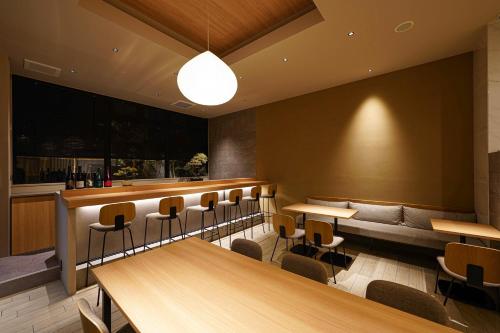 un restaurante con mesas y sillas de madera y un banco en Nico Hotel, en Osaka