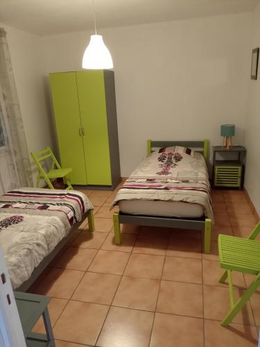 - une chambre avec 2 lits et une armoire verte dans l'établissement Les Papillons, à Labeaume