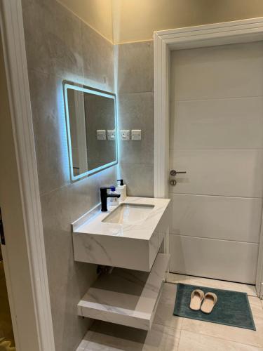 W łazience znajduje się biała umywalka i lustro. w obiekcie Elegant Apartment in Al-Narjis شقة أنيقة بثلاث غرف وصالة تسجيل ذاتي w Rijadzie