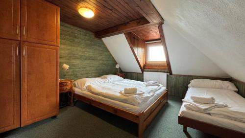 um quarto no sótão com 2 camas e uma janela em Penzion Zvonice Hojná Voda em Horní Stropnice