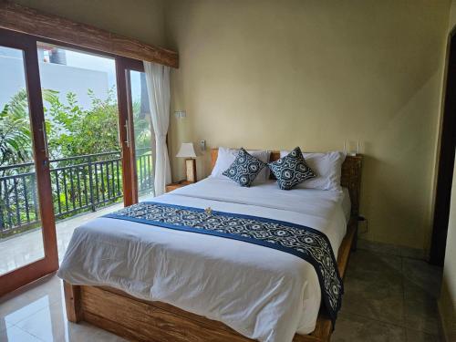 a bedroom with a large bed with a balcony at KRISNA TAPAN GUEST HOUSE in Ubud