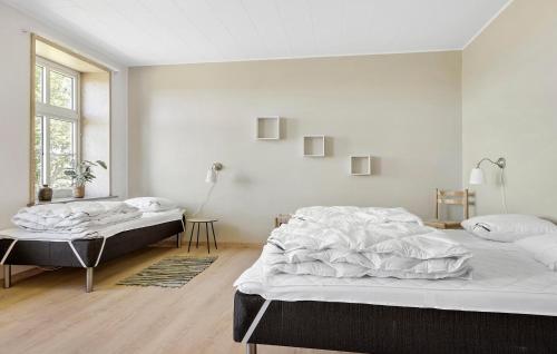 a white bedroom with two beds and a window at 6 Bedroom Stunning Home In Højer in Højer