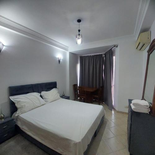 een slaapkamer met een wit bed en een tafel bij Perfect only family apartment & air cooling in Marrakesh