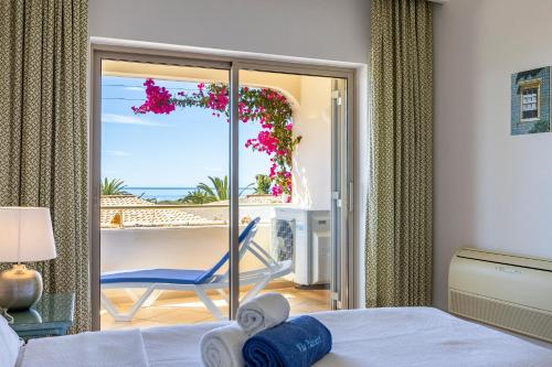 a bedroom with a bed and a balcony with a chair at Vila Palmeira Beach Resort in Lagos
