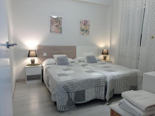 a white bedroom with a bed and two lamps at Barrón 21 in Logroño