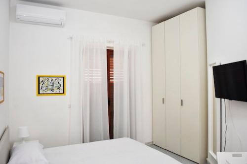 a white bedroom with a bed and a tv at Piumahouse B&B in Catanzaro