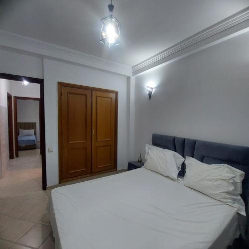 een slaapkamer met een wit bed en een bruine deur bij Perfect only family apartment & air cooling in Marrakesh