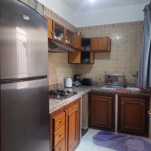 een keuken met houten kasten en een roestvrijstalen koelkast bij Perfect only family apartment & air cooling in Marrakesh
