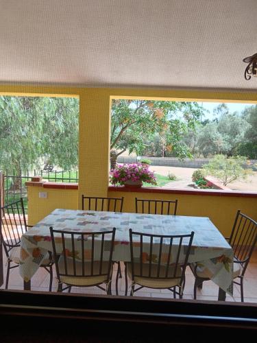 a dining room table with chairs and a large window at Villa Magnolia in Chia