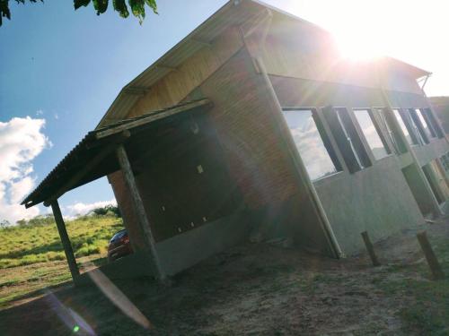 dom z otwartymi drzwiami i słońcem za nim w obiekcie Montanha Home w mieście Monte Verde