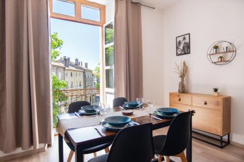 une salle à manger avec une table et des chaises et une grande fenêtre dans l'établissement T4 Cosy Centre ville Château WIFI, à Aubenas