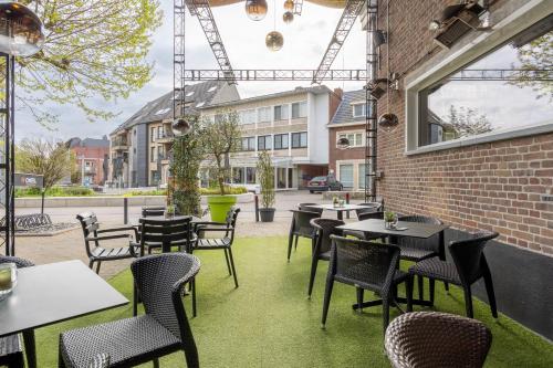 a patio with tables and chairs and a building at Hotel De Boskar Pelt in Pelt