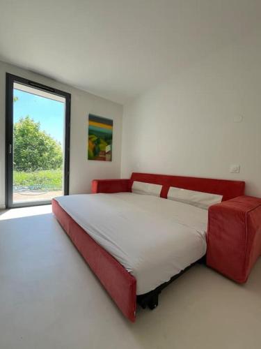 Ce lit rouge se trouve dans une chambre blanche dotée d'une fenêtre. dans l'établissement Villa moderne avec piscine, à Sainte-Foy-lès-Lyon