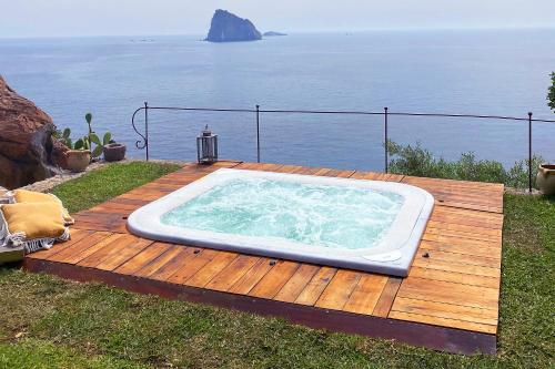 - un bain à remous installé sur une terrasse en bois à côté de l'océan dans l'établissement Villa Rocce Rosse, à Panarea