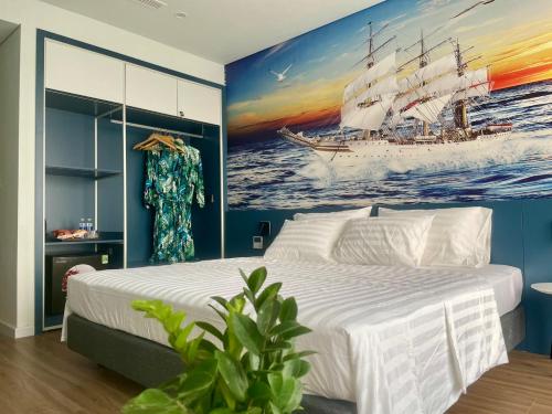a bedroom with a large white bed and a painting of a ship at Flamingo Hải Tiến in Thanh Hóa