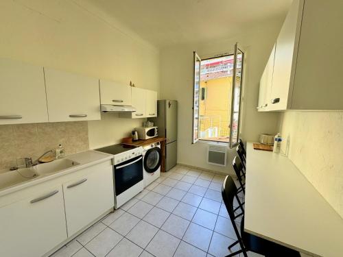 une cuisine avec des armoires blanches, un évier et un lave-vaisselle dans l'établissement Nice Magnan - 3 pièces proche mer, à Nice