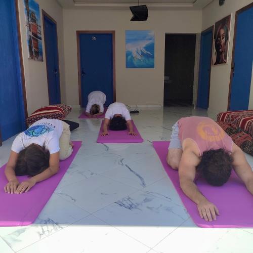 a group of people doing yoga in a room at Playa Del Sol Surf House in Tamraght Ouzdar