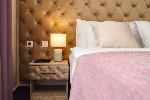 a bedroom with a bed and a lamp on a nightstand at Hotel Stella Maris - Style & Comfort in Vodice