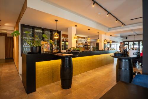 a bar in a restaurant with a yellow wall at Hotel de Boskar Houthalen in Houthalen-Helchteren