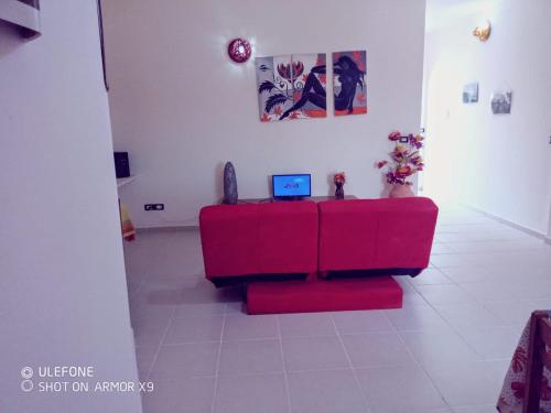 a living room with a red couch with a laptop on it at aparthotelboavistacom in Sal Rei