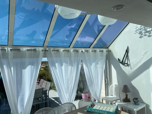 Cette chambre dispose d'une grande fenêtre avec des rideaux blancs. dans l'établissement Appartement les pieds dans l eau, à La Turballe