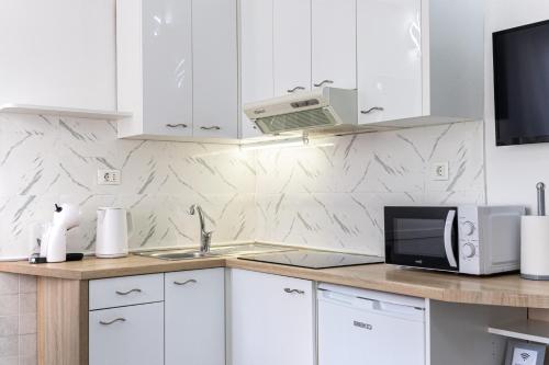a kitchen with white cabinets and a sink and a microwave at Lions Suites in Split