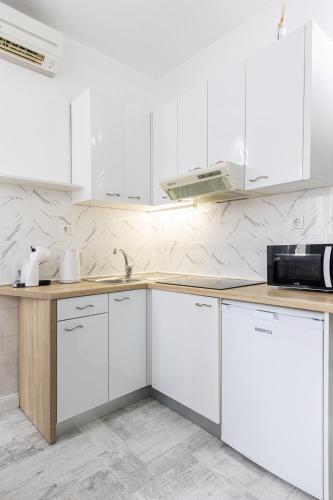 a white kitchen with white cabinets and a sink at Lions Suites in Split
