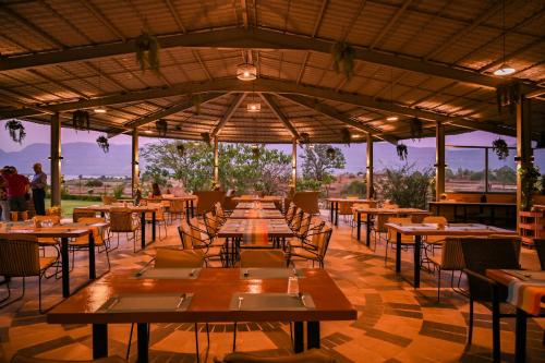 un restaurant avec des tables et des chaises en bois et une vue dans l'établissement Saj By The Lake, Malshej Ghat, à Malshej Ghat