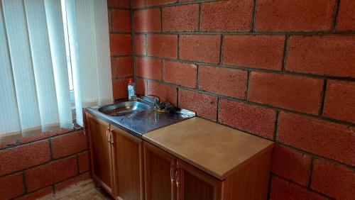 cocina con fregadero y pared de ladrillo en Lavanda Beach House, en Sevan