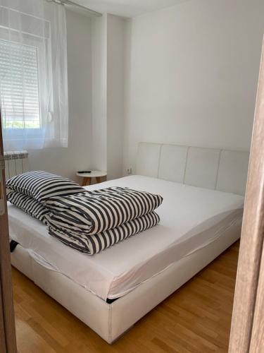 a white bed with a black and white blanket on it at Cool Apartments with FREE PARKING in Čačak