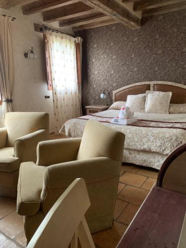a bedroom with a bed and chairs in a room at Posada Restaurante Fuenteplateada in Collado Hermoso